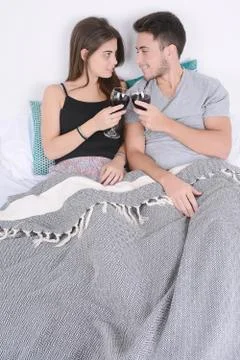 Couple drinking wine in bed. Stock Photos