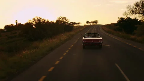 Couple driving classic cherry red convertible cabriolet car,  steadicam shot wit Stock Footage 199632145