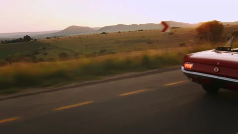 Couple driving classic cherry red convertible cabriolet car while breaking hard Stock Footage 199632328