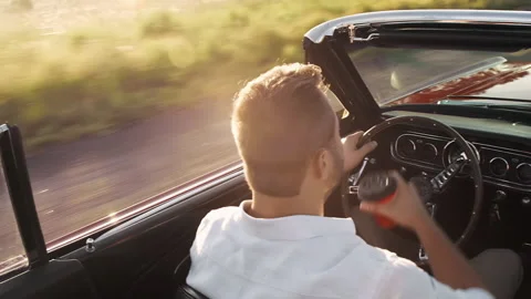 Couple driving classic cherry red convertible, cabriolet car while drinking thei Stock Footage 199632373