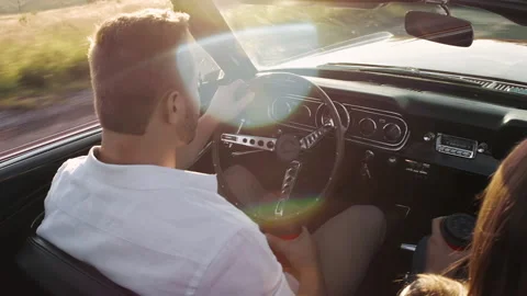 Couple driving a classic cherry red convertible, cabriolet car while drinking th Stock Footage 199632379
