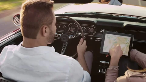 Couple driving classic cherry red convertible, cabriolet car while navigating on Stock Footage 199632380