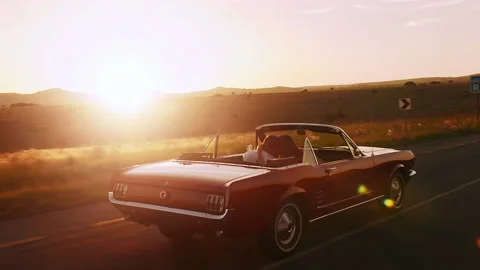 Couple driving classic cherry red convertible cabriolet car, steadicam shot with Stock Footage 199632384