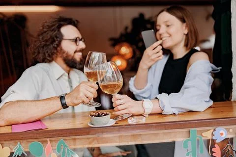 Couple during date drinking wine and making photo while sitting in bar Stock Photos