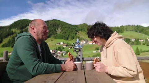 Couple eating and talking at table in scenic alpine location Stockbeeldmateriaal 318949656