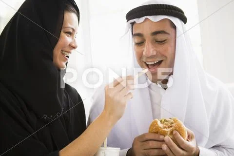Couple eating fast food in living room and smiling (high key/selective focus) Stock-Fotos