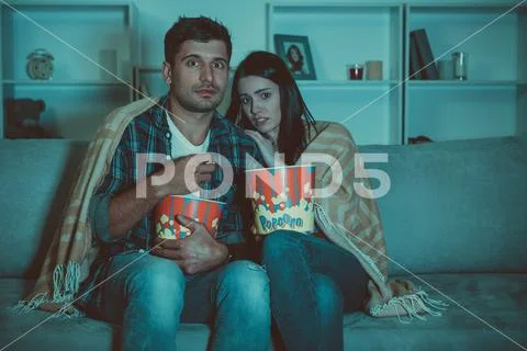The couple eating popcorn and watch a horror movie on the sofa Stock Photos
