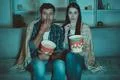 The couple eating popcorn and watch a horror movie on the sofa Photo