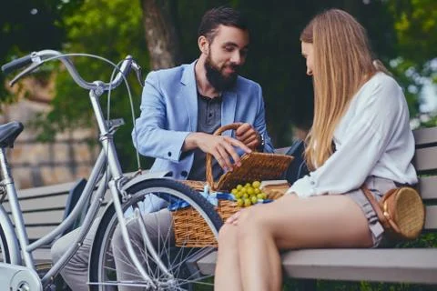 Couple eats grape on a bench in a park. Foto stock