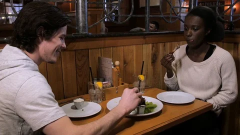 Couple eats wings at restaurant table wooden wall wooden chair wooden table r Video stock 89366065