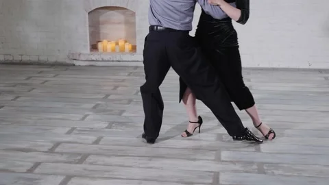 Couple in elegant suits dances classical tango by fireplace Video stock 138727923