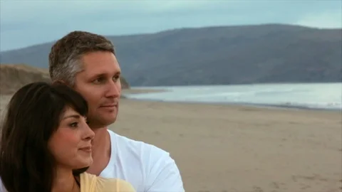 Couple embracing and looking thoughtfully out towards the ocean. Stock Footage 88406689