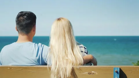 Couple embracing on bench overlooking ocean on sunny day. Vídeos de archivo 334838471