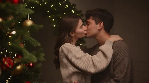 Couple embracing by a Christmas tree before sharing a gentle kiss. Stock Footage 322671374