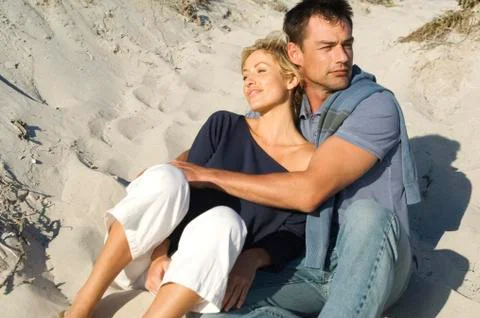 Couple embracing, sitting on the beach Stock Photos