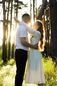 Couple embracing in a sun-drenched forest during golden hour 库存照片