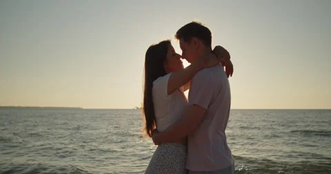 Couple embracing in sunset light standing together on the beach Stock Footage 220112535