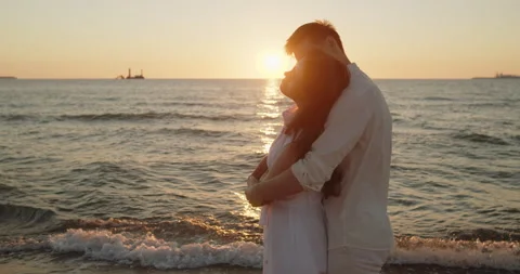 Couple embracing in sunset light standing together on the beach Stock Footage 220298317