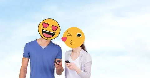 Couple with emojis over faces using mobile phones Stock Photos