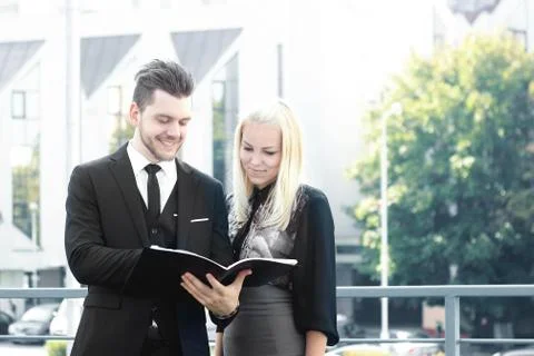 Couple of employees reading documents standing near the office Stock Photos