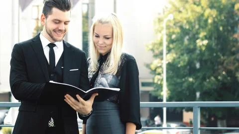 Couple of employees reading documents standing near the office Stock Photos