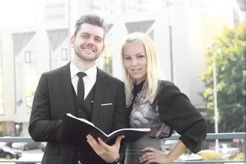 Couple of employees reading documents standing near the office Stock Photos