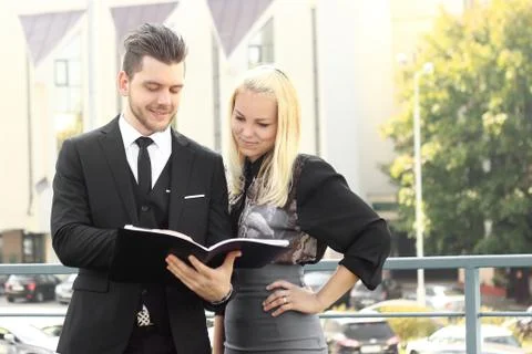 Couple of employees reading documents standing near the office Stock Photos