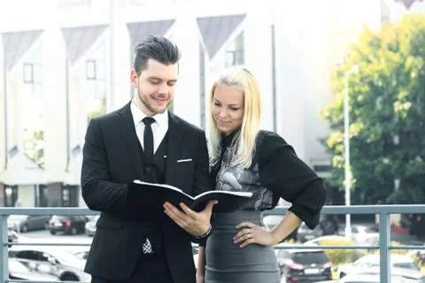 Couple of employees reading documents standing near the office Stock Photos