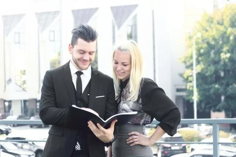 Couple of employees reading documents standing near the office Stock Photos