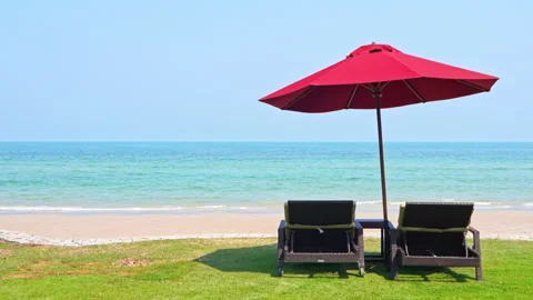 Couple of empty beach beds under red parasol on majestic tropical beach on Stock Footage 152338058