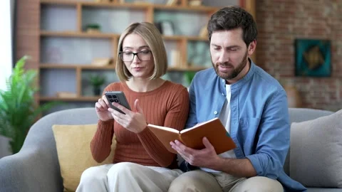 Couple is engaged in home expense tracking using an application on a mobile  Stock Footage 323806870