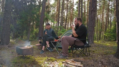 Couple enjoying barbecue picnic while camping in pine forest 스톡 동영상 327132527