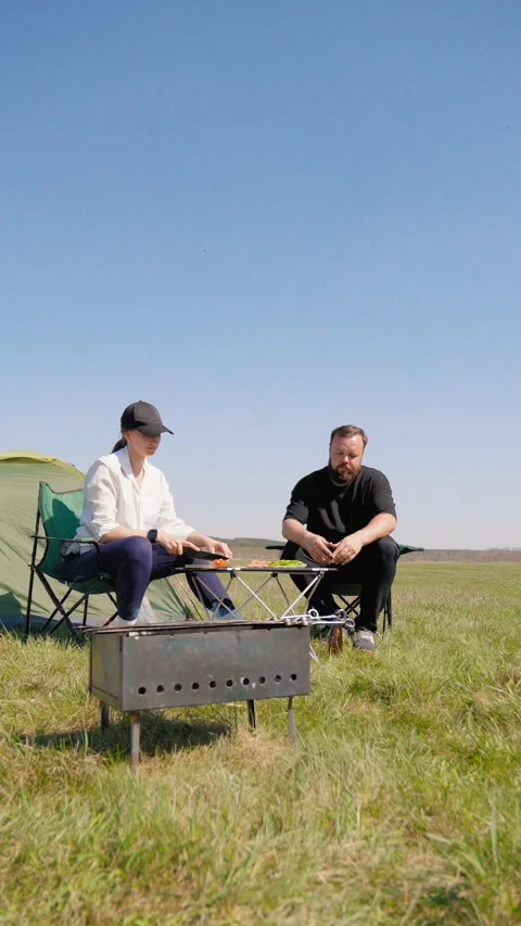 Couple enjoying barbecue picnic while camping 库存影片 344603816