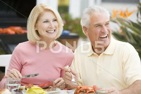 Couple enjoying a barbequed meal in the garden Stock-Fotos