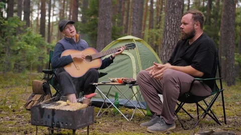 Couple enjoying camping picnic with guitar music and barbecue Видео 327133353