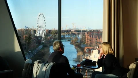 Couple enjoying a drink with views over the canal and ferris wheel from the Sky Vídeo Stock 336689904