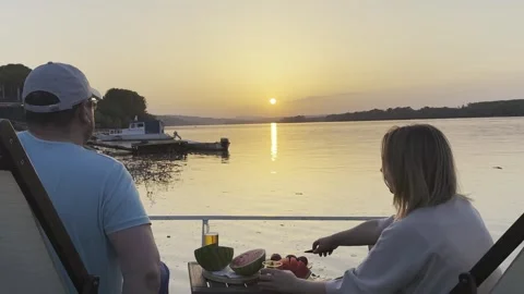 Couple Enjoying Drinks and Watermelon by River at Sunset Stock Footage 334571237