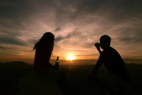 Couple enjoying drinks while watching the sunset from a mountain top in Greece Stock Photos