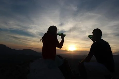 Couple enjoying drinks while watching sunset Stock Photos