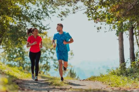 Couple enjoying in a healthy lifestyle while jogging on a country road through Stock Photos