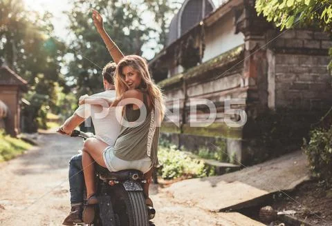 Couple enjoying motorcycle ride on village road Stock Photos