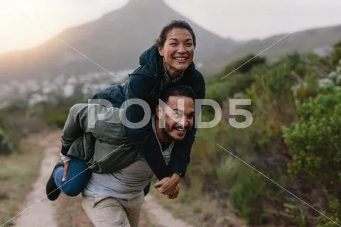 Couple enjoying piggyback ride in countryside Stock Photos