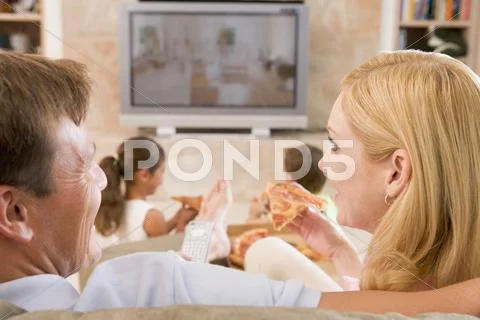 Couple enjoying pizza in front of tv Stock Photos