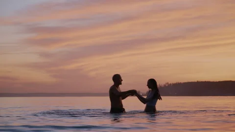 Couple enjoying a romantic sunset while playing in the ocean Stock-Footage 316360371