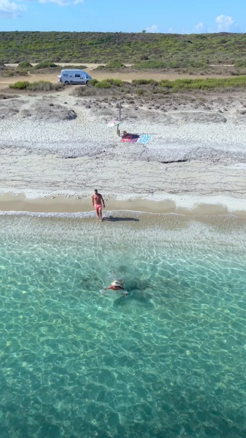 Couple enjoying the sun and waves at Le Saline Beach in Sardinia Italy Stock Footage 346350840