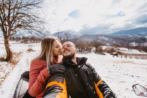 Couple enjoying while driving quad bike on top of mountain at winter time Stock Photos