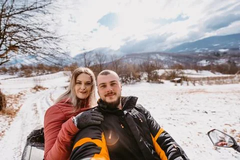 Couple enjoying while driving quad bike on top of mountain at winter time Stock Photos