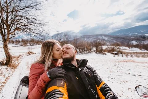 Couple enjoying while driving quad bike on top of mountain at winter time Foto stock
