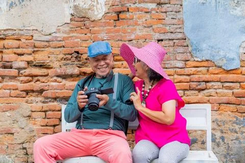 Couple enjoys conversation while taking pictures in front of a brick wall d.. Stock Photos