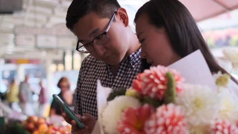 Couple enjoys exploring market while checking cellphone together Stock Footage 312687763
